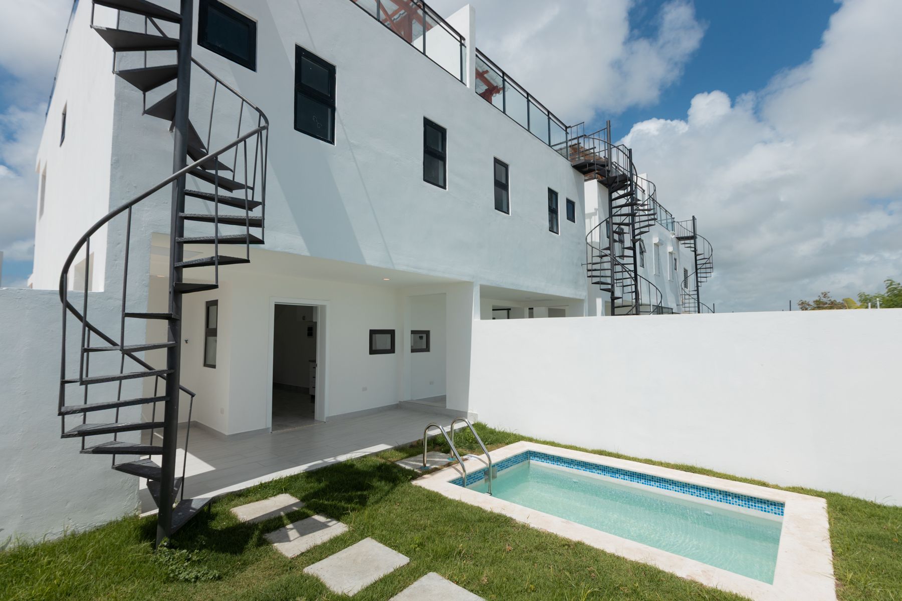 Patio trasero con piscina y escalera de caracol hacia la azotea